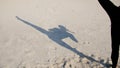 On the sand you can see the shadow, the silhouette of an athletic girl, who performs lifting of the legs, fulfills the