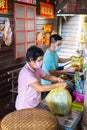 Sandakan, Malaysia - January 06, 2022: sales women packs the goods in a plastic bag. Fish market in Sabah, Borneo. The shops are