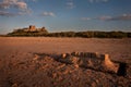 A sandcastle on a beach with a real castle in the background