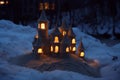 sandcastle with litup windows using a flashlight at dusk with snow around Royalty Free Stock Photo