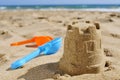 Sandcastle and toy shovels on the sand of a beach Royalty Free Stock Photo