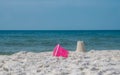 Sandcastle on white ocean beach sand. Colorful pink toy bucket lying beside seaside sandcastle. Royalty Free Stock Photo