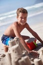 Sandcastles are what childhood dreams are made of. a cute little boy building a sandcastle at the beach.