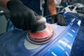 Sander grinding painted bumper in car workshop