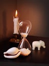 Sandglass, toy elephant and white shell