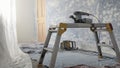 An orbital sander being used to strip the walls in a dusty room
