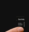Sandisk memory card adaptor held between two fingers. Close up