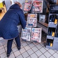 Woman Bending Down Or Stooping To Buy A Newspaper