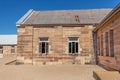 Sandstone convict brick made building with corrugated iron roof, open windows, pebbled courtyard against blue sky