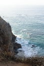 Sandstone path overlooking cliff side, pacfic ocean expanse, and waves on the shore