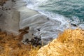 Sandstone path overlooking cliff side, pacfic ocean waves on a sandy beach, rocks
