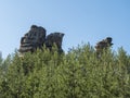 Sandstone rock pillar in spring landscape in Lusatian Mountains with fresh deciduous and spruce tree forest. Blue sky