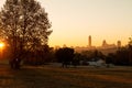 Sandton skyline at sunrise with trees and park with sun shining through the tree