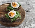 Sandwich with arugula, boiled egg and mustard on a wooden board. Royalty Free Stock Photo