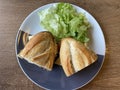 Sandwich baguette bacon and fried egg with salad on black white plate on wooden table Royalty Free Stock Photo