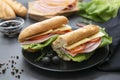 Sandwich with baguette bread, ham, lettuce, tomatoe over dark background. Breakfast or fast food Royalty Free Stock Photo