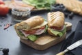 Sandwich with baguette bread, ham, lettuce, tomatoe over dark background. Breakfast or fast food Royalty Free Stock Photo