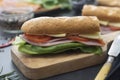 Sandwich with baguette bread, ham, lettuce, tomatoe over dark background. Breakfast or fast food Royalty Free Stock Photo