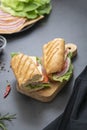 Sandwich with baguette bread, ham, lettuce, tomatoe over dark background. Breakfast or fast food Royalty Free Stock Photo