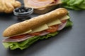 Sandwich with baguette bread, ham, lettuce, tomatoe over dark background. Breakfast or fast food Royalty Free Stock Photo