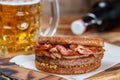 Sandwich with beef, fried onion, cheese and bacon with granular mustard. Beer and snack on the table Royalty Free Stock Photo