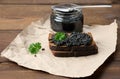 Sandwich with black caviar on a slice of rye bread and a jar with a spoon, a delicious snack on the table Royalty Free Stock Photo