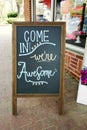 Sandwich board sign in front of a small business with Come In We`re Awesome message written in chalk Royalty Free Stock Photo