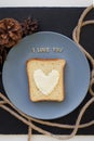 sandwich for breakfast in form of heart with cheese on a blue plate and black background with cones inscription I love you Royalty Free Stock Photo