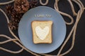 sandwich for breakfast in form of heart with cheese on a blue plate and black background with cones inscription I love Royalty Free Stock Photo