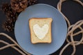 Sandwich for breakfast in form of heart with cheese on a blue plate and black background with cones Royalty Free Stock Photo