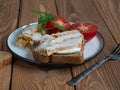 Sandwich with chicken ham and sliced tomato on a ceramic plate on a wooden table Royalty Free Stock Photo