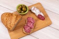 Sandwich of dried sausages, olives and a loaf of whole grain bread on a wooden board. The concept of simple affordable food Royalty Free Stock Photo