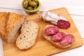 Sandwich of dried sausages, olives and loaf of whole grain bread on wooden board. Concept of simple affordable food Royalty Free Stock Photo