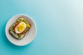 Sandwich with egg and avocado on a white plate on a blue background, top view Royalty Free Stock Photo