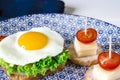 Sandwich with egg, ham, cheese, toast and salad leaves lies on a plate with tomato and dill Royalty Free Stock Photo