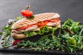 Sandwich with fillet grilled chicken, fresh vegetables, cheese and greens on black shale board over black stone background Royalty Free Stock Photo