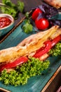 Sandwich with fillet grilled chicken, lettuce, tomatoes, cheese and traditional bread loaf out of the oven on dark background. Royalty Free Stock Photo