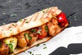 Sandwich from fresh pita bread with fillet grilled chicken and vegetables on dark wooden background. Royalty Free Stock Photo