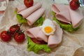 Sandwich with fried eggs, sausage, lettuce and sauce.