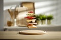 Sandwich ingredients separated and levitating in the air above the wooden table top. Blurred kitchen background.