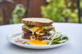 Sandwich made from slices of white bread and filled with roasted melted beef steak, cheese, sunny side up egg and vegetables. Royalty Free Stock Photo