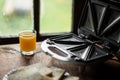 sandwich maker and a glass of juice on the background of an old-fashioned window. Preparing a quick morning breakfast, snack