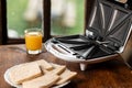 sandwich maker and a glass of juice on the background of an old-fashioned window. Preparing a quick morning breakfast, snack