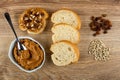 Sandwich with peanut pasta, spoon in bowl with peanut butter, slices of bread, heap of sunflower seeds and raisin on table. Top Royalty Free Stock Photo