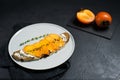 Sandwich with persimmon and soft cheese on a black background.