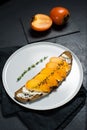 Sandwich with persimmon and soft cheese on a black background.