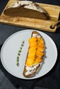 Sandwich with persimmon and soft cheese on a black background.