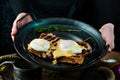 Sandwich with poached egg and bacon on a plate in the hands of a chef On a black background. Royalty Free Stock Photo