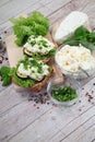 Sandwich with white cream cheese and herbs, chives and basil on a rustic wooden board Sandwich of cheese with herbs. Wooden backgr