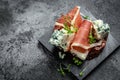 Sandwich with prosciutto, blue cheese. antipasti with red wine. Appetizer on a slate board